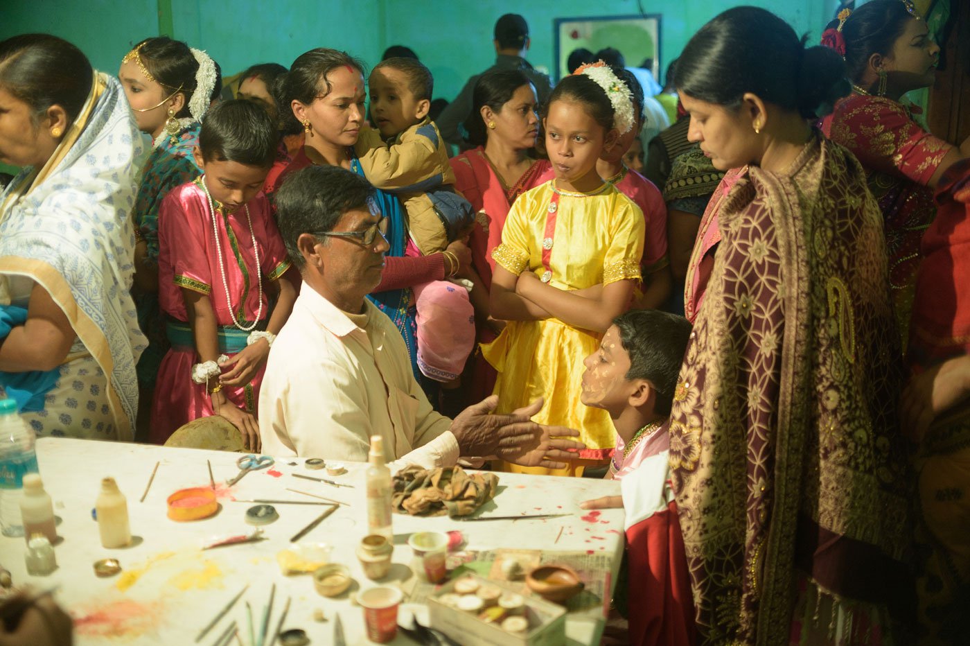 Parents and guardians assemble to have their children's makeup done by Anil Sarkar (centre), a teacher in the local primary school