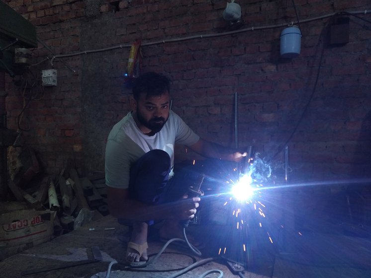 Amir uses a hand operated drilling machine (left) to make a hole into a plate that will be welded onto the multi-gym. Using an arc welder (right), he joins two metal pieces