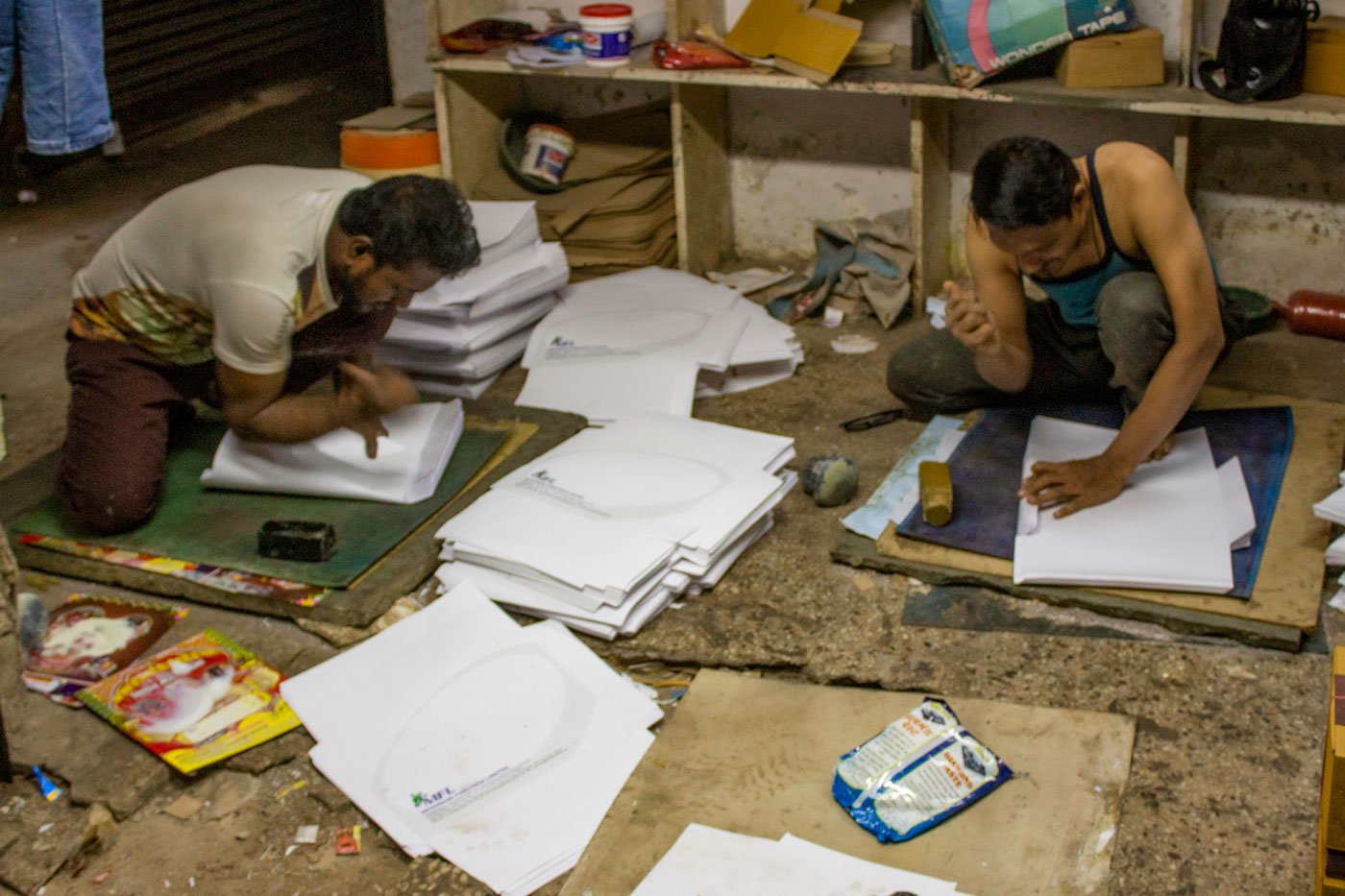 Abdul Majeed Abdul Karim Sheikh (left) and Yusuf Khan Chotukhan Pathan of Sameer envelopes are using their side of their palms on the folded dhapa and pendi to make a sharp crease