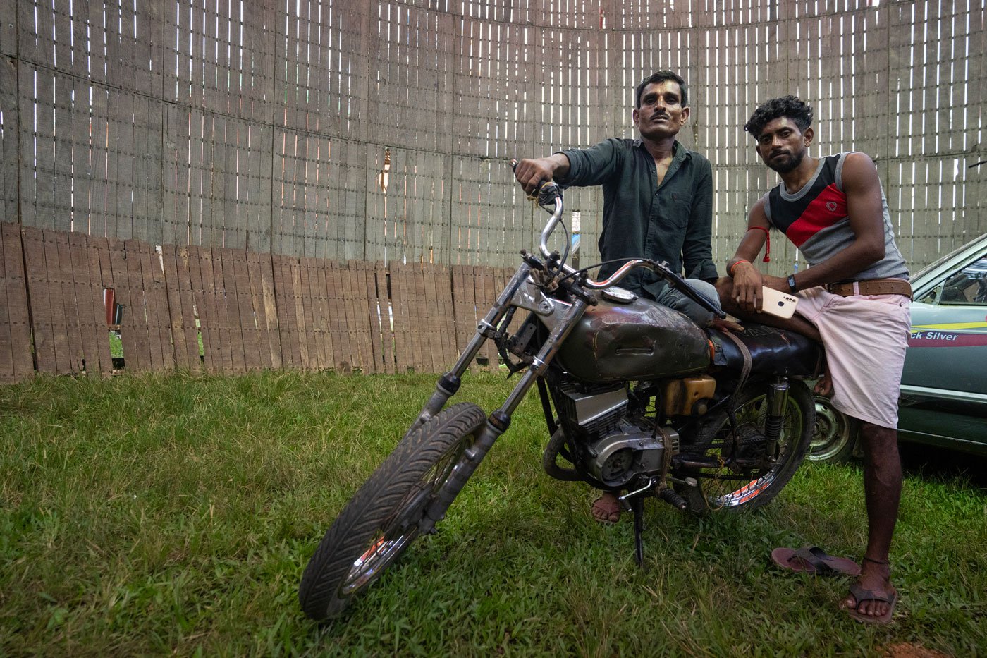 Jagga Ansari (left) and Pankaj Kumar (right) pose for a portrait inside the ‘well of death’ with one of the bikes they ride during the act