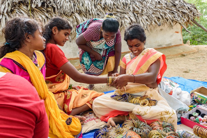 Right: The bangle seller helps a customer try on glass bangles