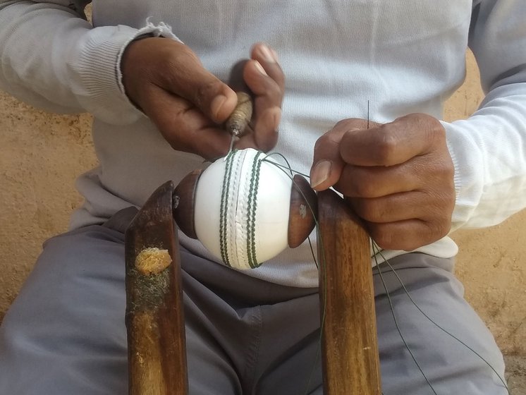 Pappan, 45, (left) must estimate correctly where to poke holes and space them accurately. It takes 80 stitches to makes holes for the best quality balls, and it can take a karigar more than 30 minutes to stitch four parallel rows of seam