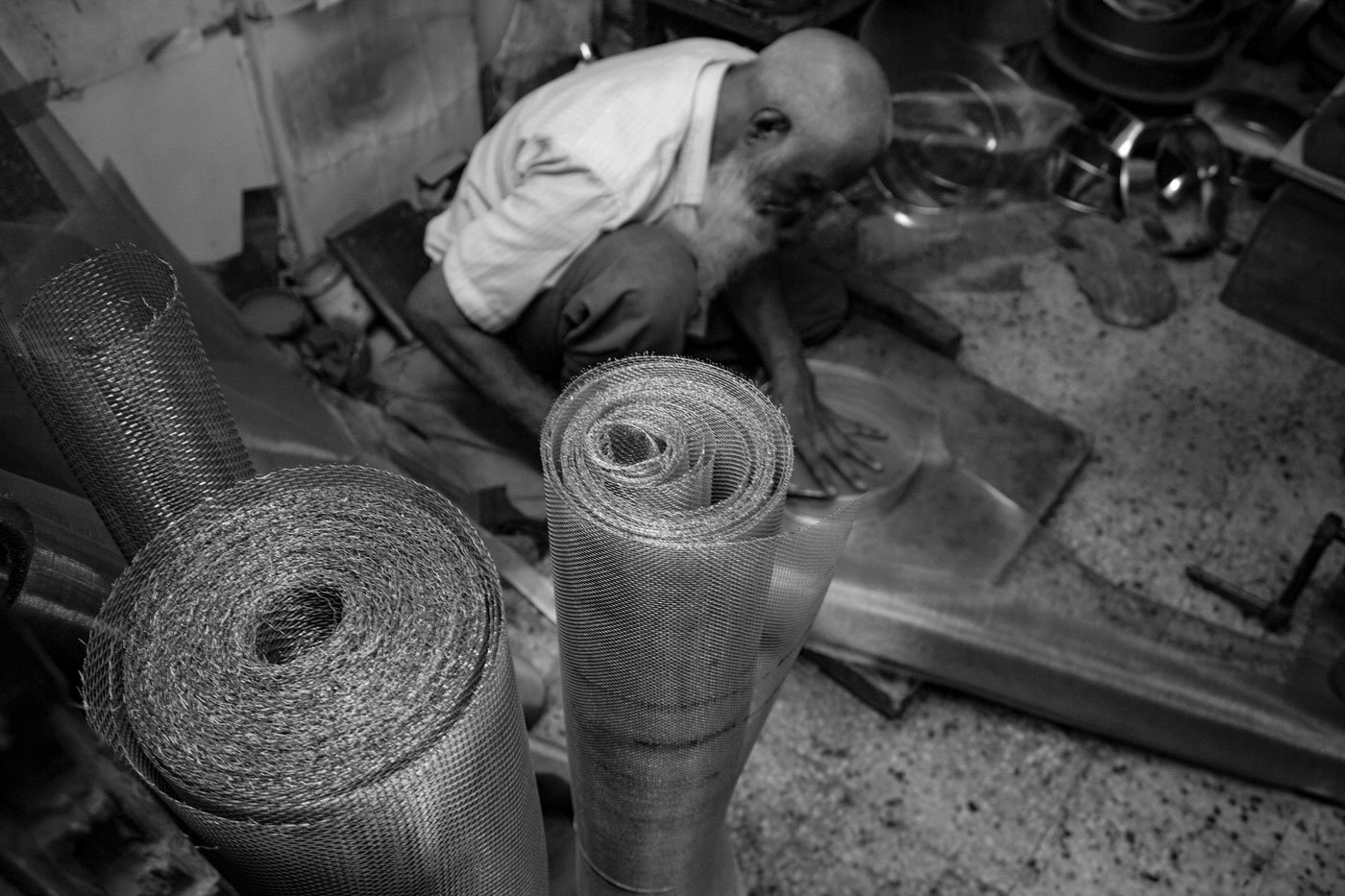 Seventy-five-year-old Shabbir H. Dahodwala in the press, folding and pressing the tin sheets