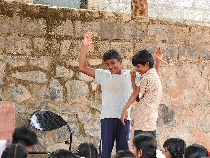 Meanwhile, the older students gather on stage for the daily assembly. Today is 'Comedy Day' and whoever has something prepared or wants to improvise is given time to do so. These two boys enact a short skit on ‘The elephant and the tree’