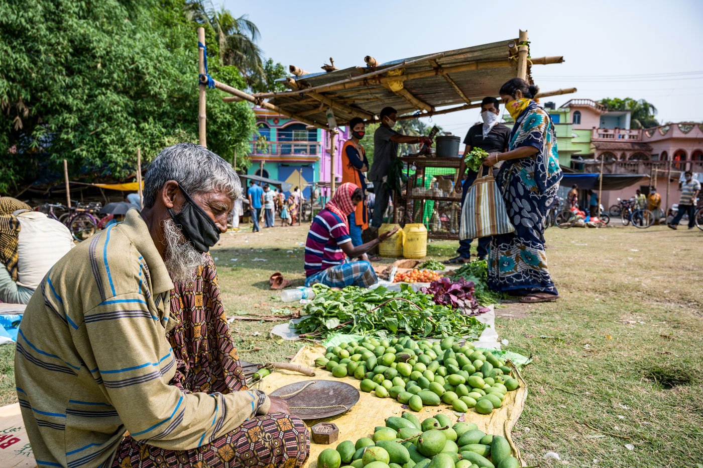 Sadhu Shaikh, 56, has found a spot just off the filed, away from where the other vendors are sitting. He is selling mangoes and vegetables from his own small farmland.