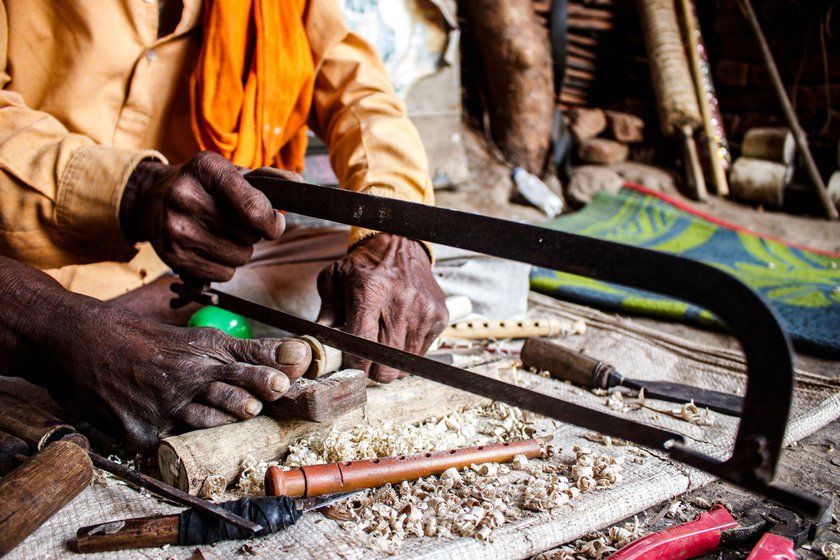 Right: He is cutting off the extra wooden part, which he kept for margin to help correct any errors while crafting the shehnai