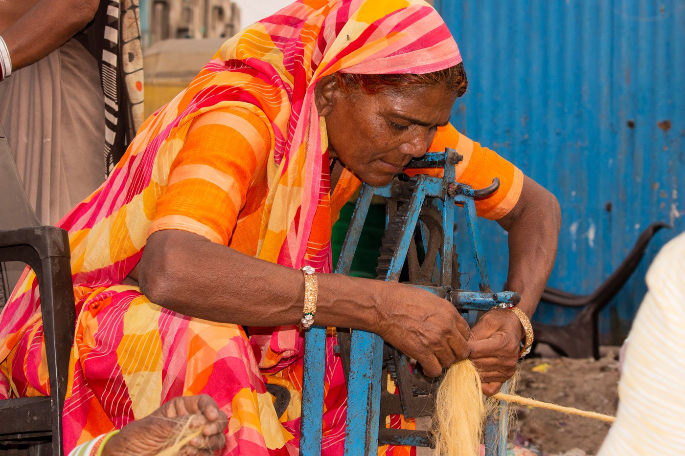 Rupa Rajbhoi attaches a length of twisted fibre to the larger spinning wheel