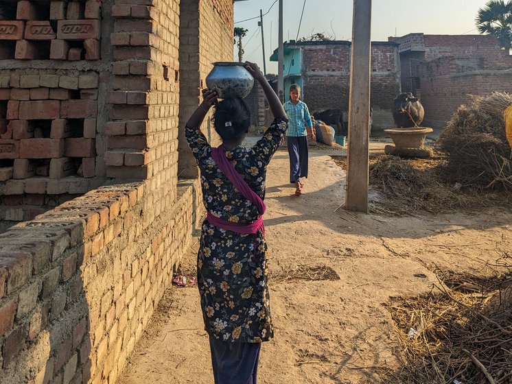 Right: Gayatri Kumari, who lives in the Dalit colony of Akabarpur panchayat, carrying a water-filled tokna (pot) from the only hand pump in her colony. She says that she has to spend at least one to two hours daily fetching water