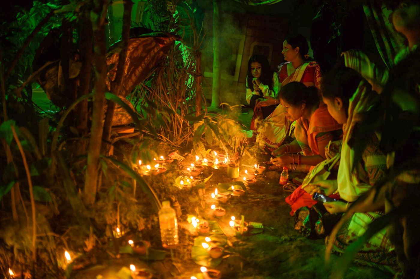 Women light diyas and incense sticks around a figure of Kaliyo Naag. The ritual is part of the prayers performed before the festival begins