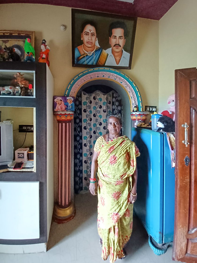 Lakshmi standing in Lakshmi Vilas, the house she built by selling and trading jackfruits. On the wall is the painting of her and her husband that she had commissioned