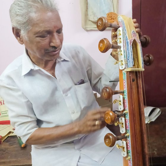 Narayanan (left) showing the changes in the structures of the veena where he uses guitar keys to tighten the strings.