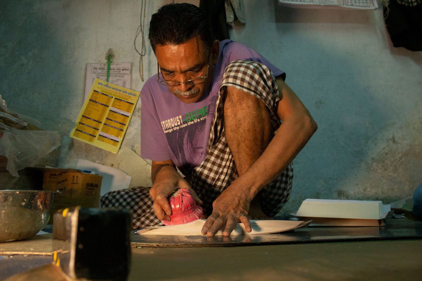 Abdul Muttalib Mohammad Ibrahim Ansari at Taj Envelopes is applying lai (a glue made from either refined flour or tamarind seed) on the covers using a putlo , a little bundle-like tool made using thin strips of cloth tied inside a piece of rexine