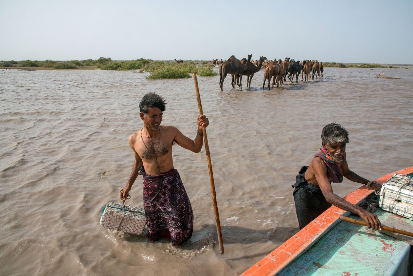 Aadam Jat (left) and a fellow herder getting on the boat to return to their village after the camels have left the shore with another herder