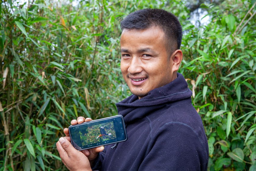 Micah holding up a photo of a Rufous-necked Hornbill he shot on his camera.