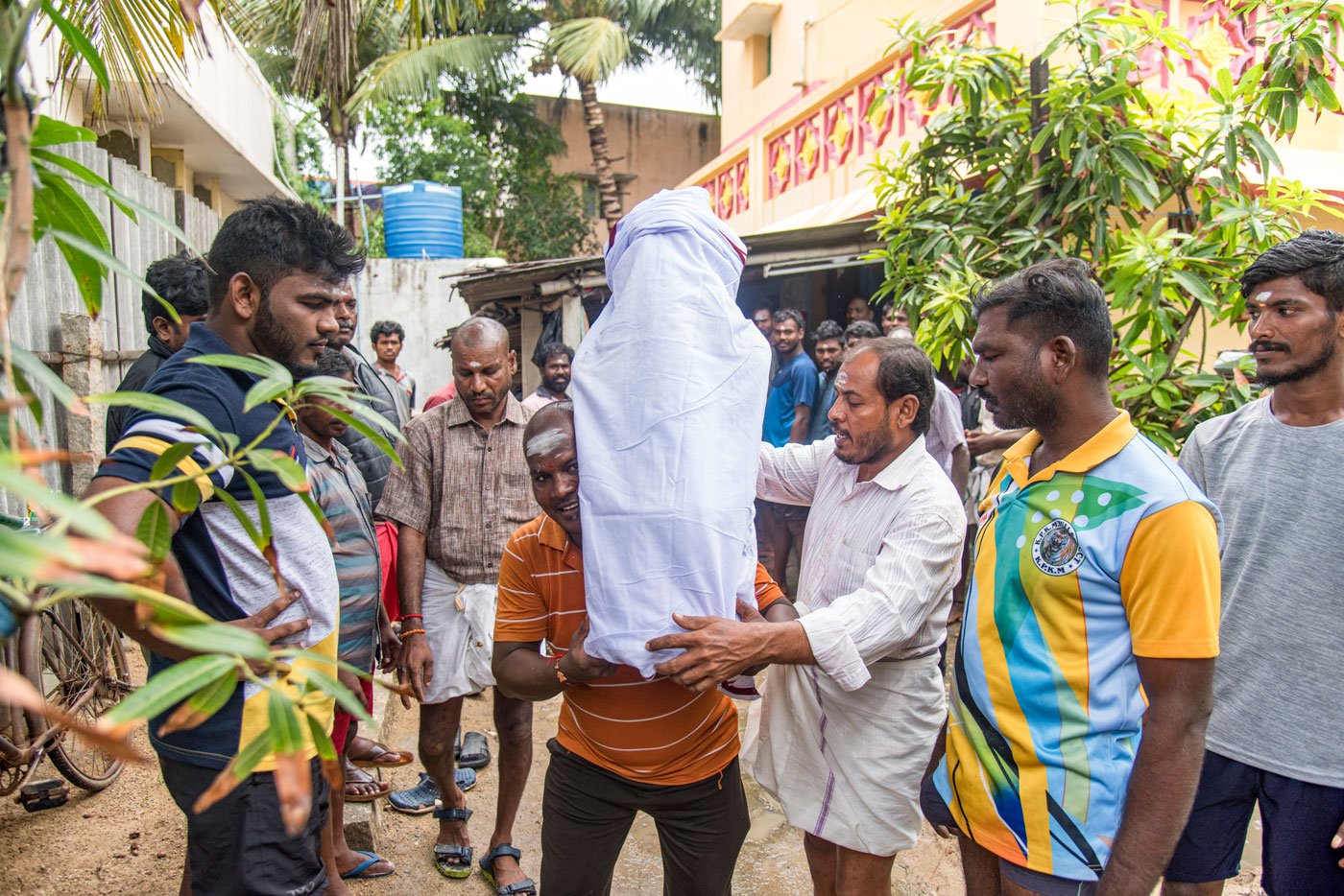 Fishermen taking the wrapped idols from Dilli anna at his house in Athipattu.
