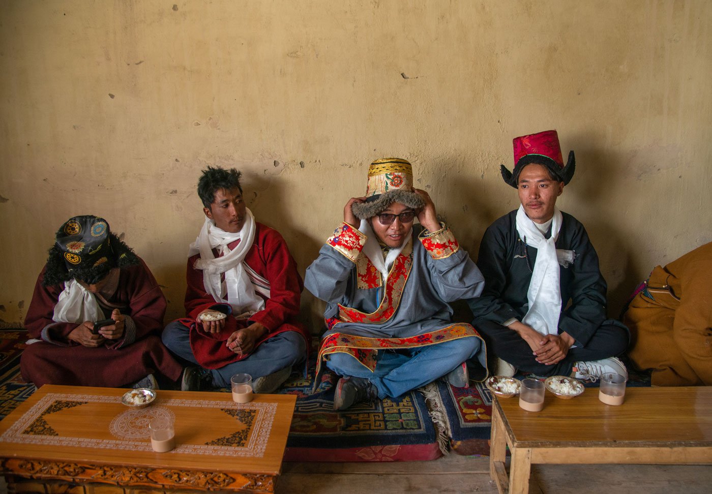 Thankchok Dorje and his friends eating their lunch and drinking salt tea inside the community hall of Punguk Gompa