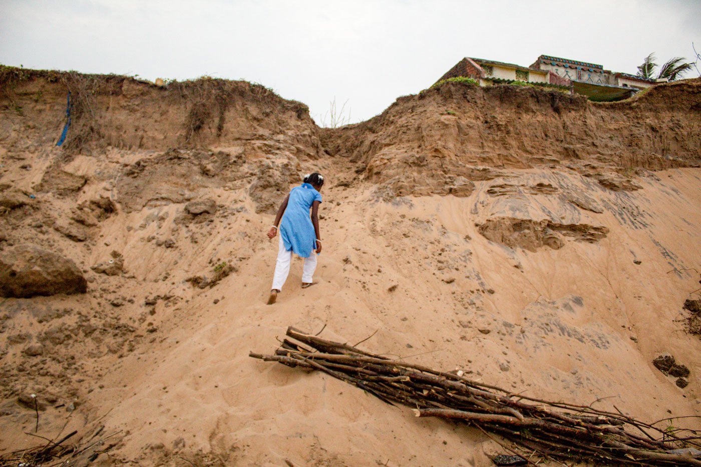 A student from Podampeta village walks home from school. The route has been damaged due to years of relentless erosion by the sea; the entire village has also migrated due to this.