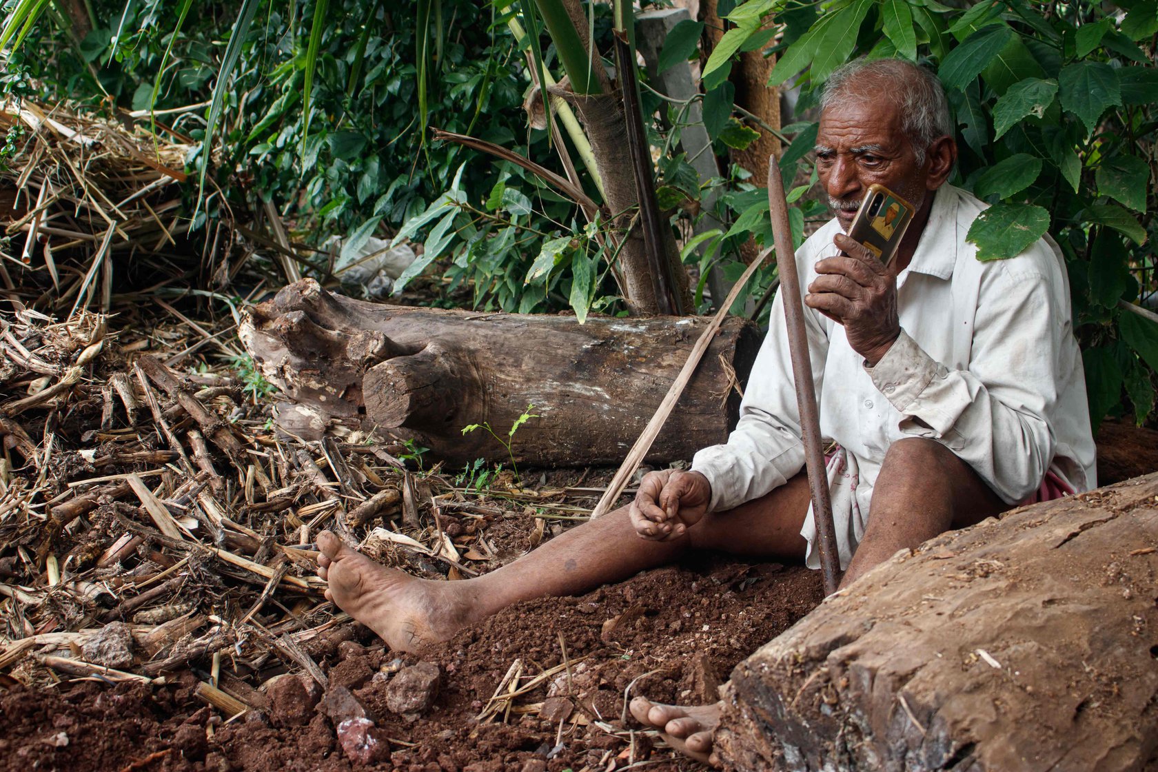 Narayan Gaikwad attending a call on his mobile while digging holes for the jhopdi