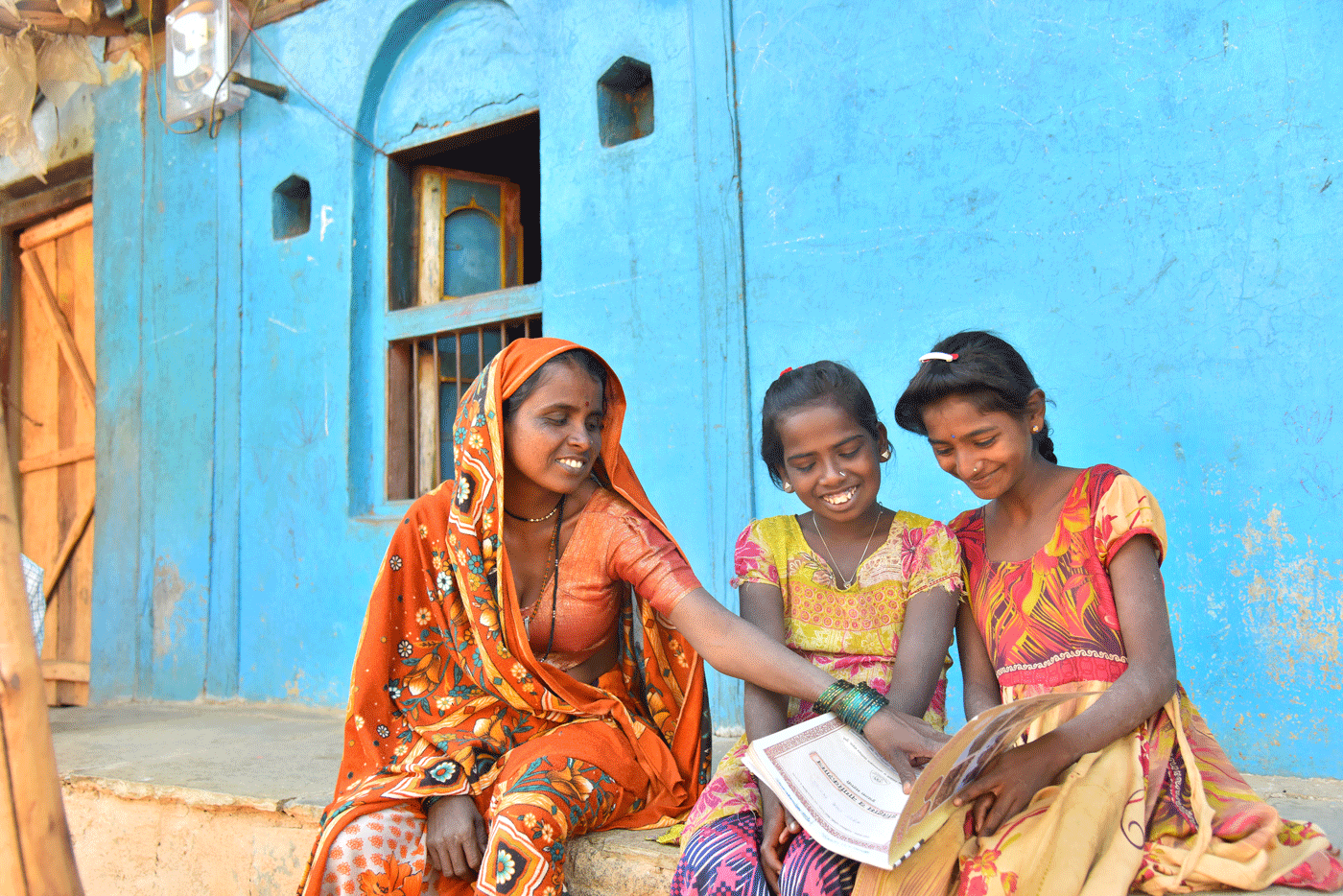 A woman and two girls looking at a book.