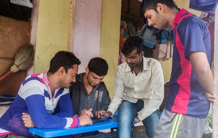 Young men playing a game on their smartphones in the primary school in Bhendavade.