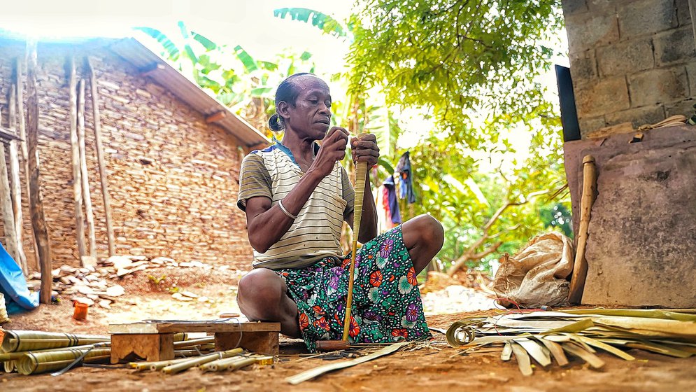 Sonsaay Baghel wrapping palm leaves around the hollow bamboo to decorate a tupki.