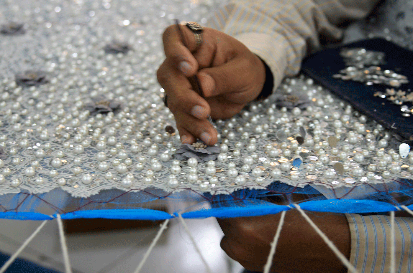 Close up of hand while doing zari work.