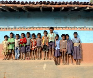Santhal children standing in front of painted wall
