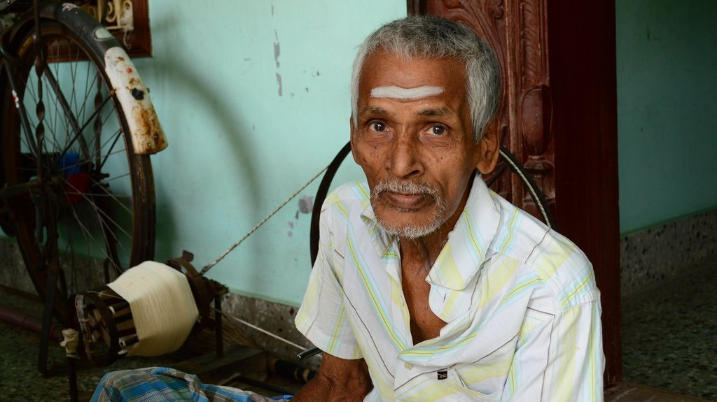 Old man in front of spinning wheel