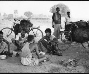 Group of men from different castes eating lunch beside their coal laden cycles