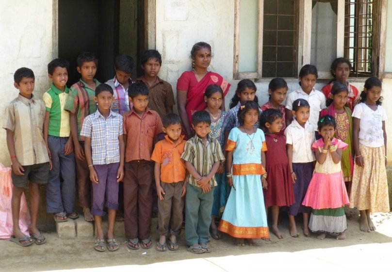 The students and teacher Vijaylaxmi just outside their single-classroom school